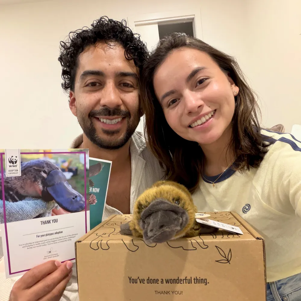 Yen and Nico holding a WWF-Australia platypus symbolic adoption kit, with the plush platypus and adoption certificate